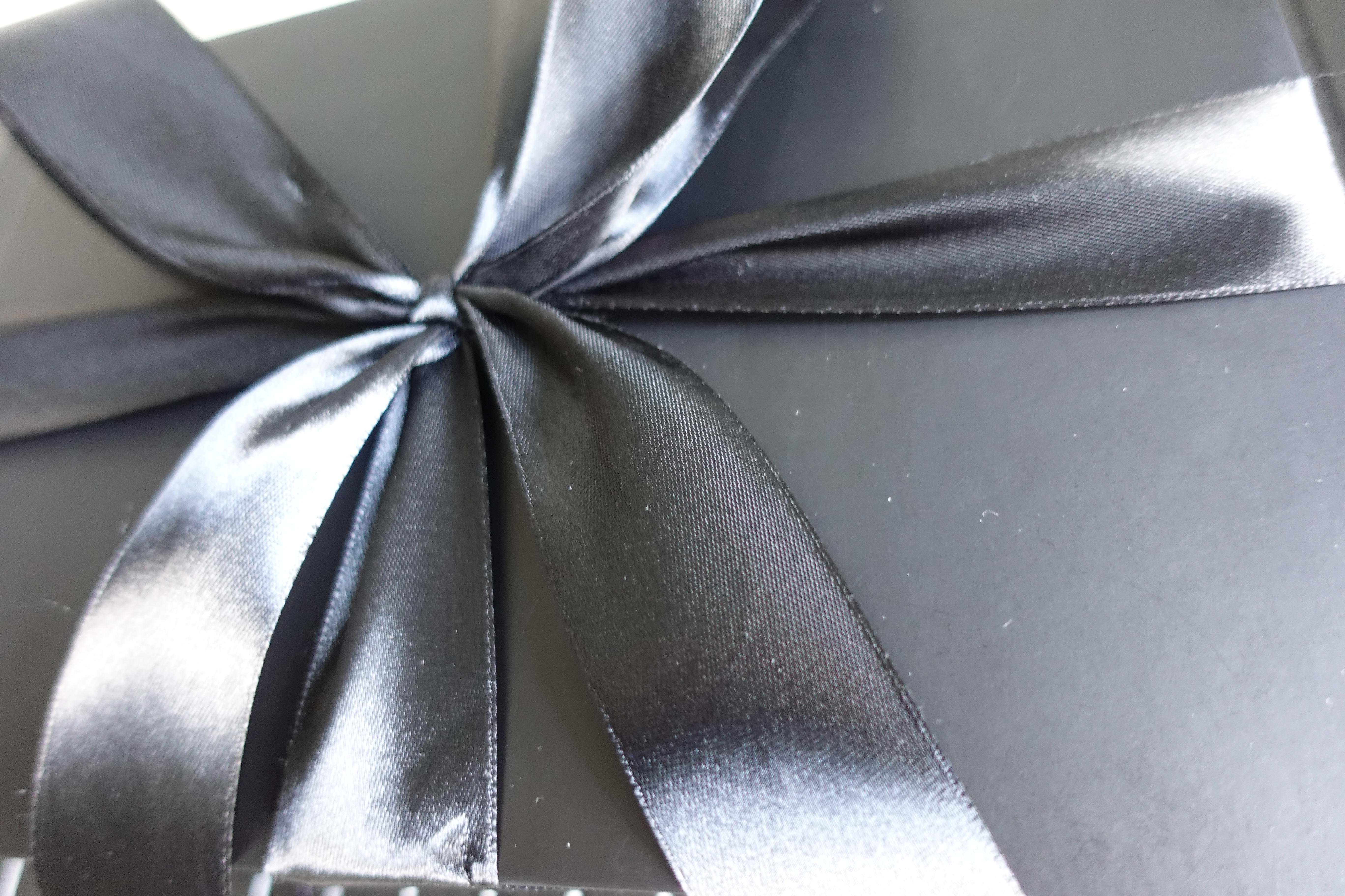 Close-up of a black satin ribbon tied around a gift box
